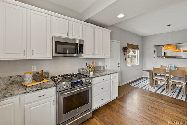 kitchen featuring decorative light fixtures, appliances with stainless steel finishes, dark wood-type flooring, white cabinets, and baseboards