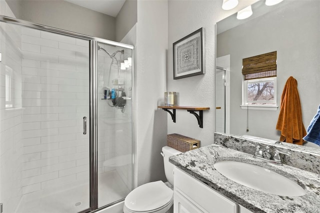 full bathroom featuring a textured wall, vanity, a shower stall, and toilet