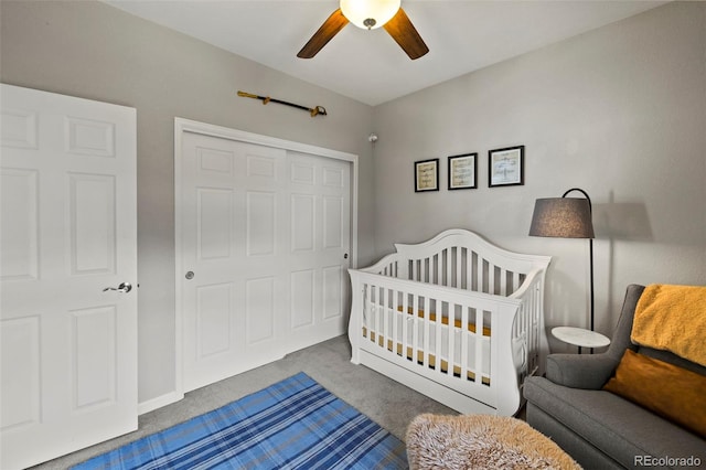 carpeted bedroom featuring a ceiling fan, a nursery area, and a closet