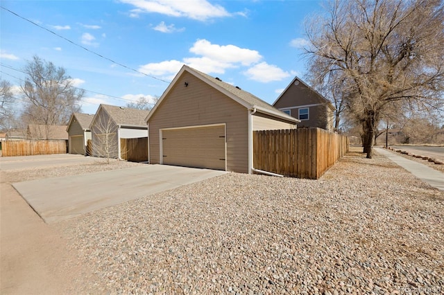 view of side of home with a garage, an outbuilding, and fence