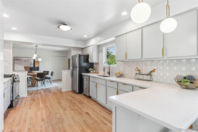 2180 Myrtlewood Ln, Lakewood, CO 80215 - kitchen featuring stainless steel appliances, light countertops, decorative backsplash, light wood-type flooring, and decorative light fixtures