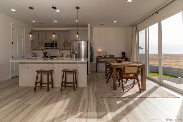 kitchen with a kitchen island with sink, gray cabinets, appliances with stainless steel finishes, and a wealth of natural light