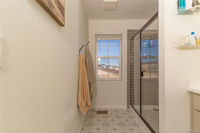 bathroom featuring walk in shower, vanity, and a textured ceiling