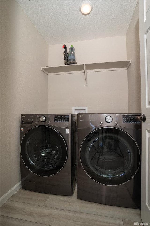 laundry room with washing machine and dryer and light hardwood / wood-style floors