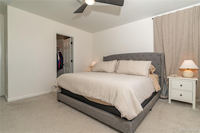 carpeted bedroom featuring ceiling fan, a closet, and a walk in closet