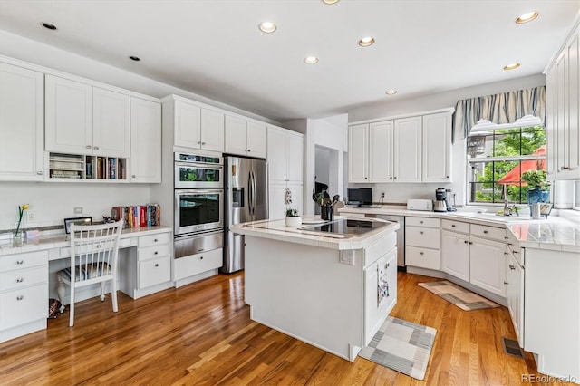 9411 E Hidden Hill Ln, Lone Tree, CO 80124 - kitchen featuring stainless steel appliances, built in desk, white cabinetry, recessed lighting, and light wood-style floors