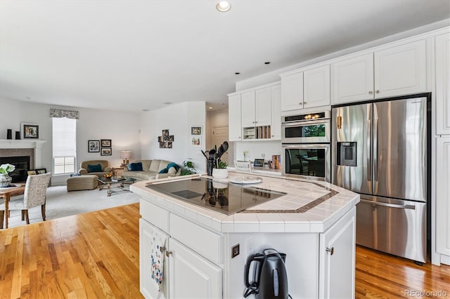 9411 E Hidden Hill Ln, Lone Tree, CO 80124 - kitchen featuring appliances with stainless steel finishes, tile counters, a center island, white cabinets, and open floor plan