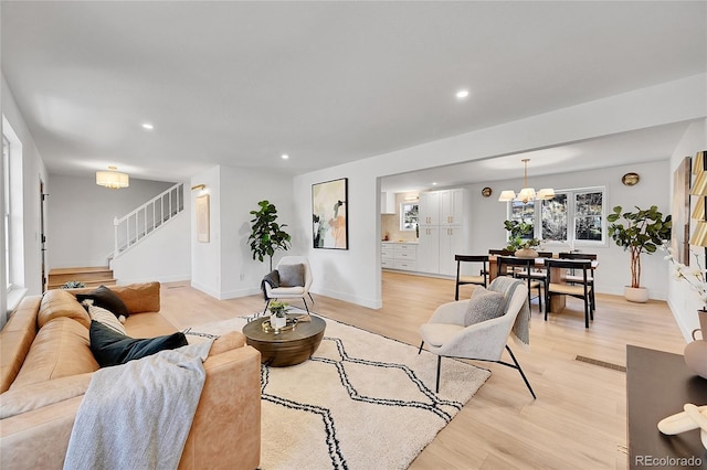 living area featuring light wood-style floors, recessed lighting, a notable chandelier, and stairs