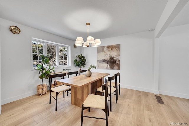 dining room with a chandelier, baseboards, visible vents, and light wood-style floors