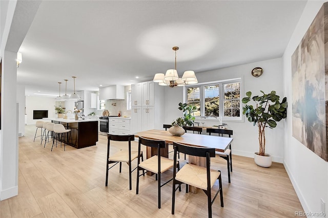 dining room with light wood-style flooring, a chandelier, and baseboards