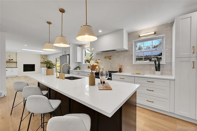 kitchen featuring a sink, decorative backsplash, light wood finished floors, plenty of natural light, and gas range