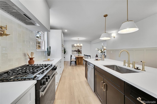 kitchen featuring a sink, light countertops, wall chimney range hood, and black gas range