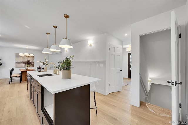 kitchen featuring light countertops, light wood-type flooring, a sink, and a kitchen island with sink