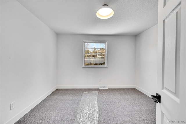 unfurnished room featuring carpet floors, visible vents, a textured ceiling, and baseboards