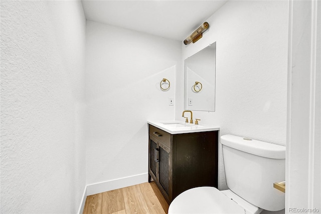 bathroom featuring baseboards, vanity, toilet, and wood finished floors