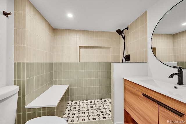 bathroom featuring toilet, walk in shower, tile walls, and vanity