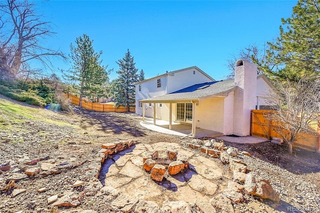 rear view of property with a fenced backyard, a patio, and a chimney