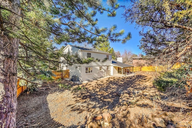 view of side of property with central air condition unit, a patio area, a chimney, and fence