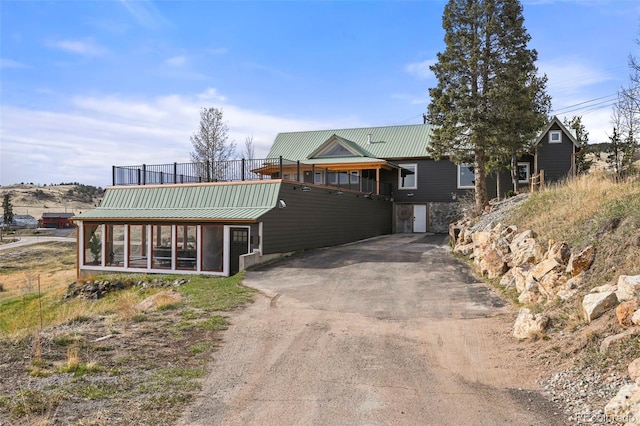 137 Hayden St, Cripple Creek, CO 80813 - view of front of property featuring stone siding, driveway, metal roof, and a sunroom