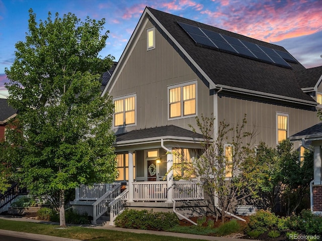 8012 E 50th Dr, Denver, CO 80238 - back of house at dusk featuring a porch, a shingled roof, solar panels, and stairs