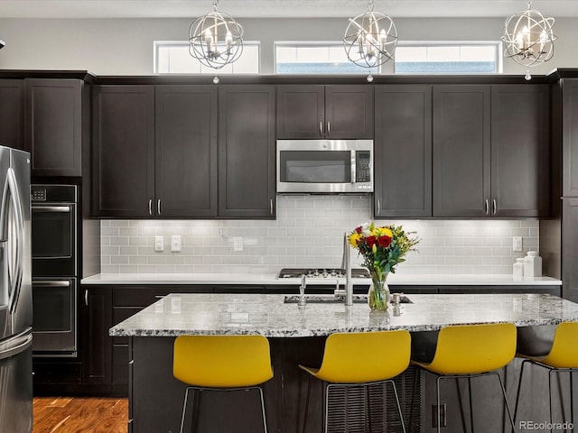 8012 E 50th Dr, Denver, CO 80238 - kitchen with stainless steel appliances, a kitchen bar, light stone countertops, wood finished floors, and hanging light fixtures