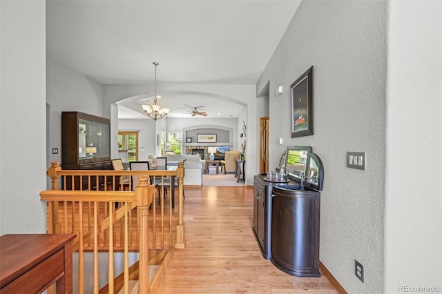 6475 Umber Cir, Arvada, CO 80007 - hallway with arched walkways, light wood-style flooring, a textured wall, and a chandelier