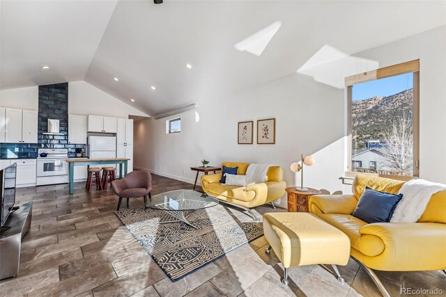 living room featuring a mountain view, vaulted ceiling, and a healthy amount of sunlight