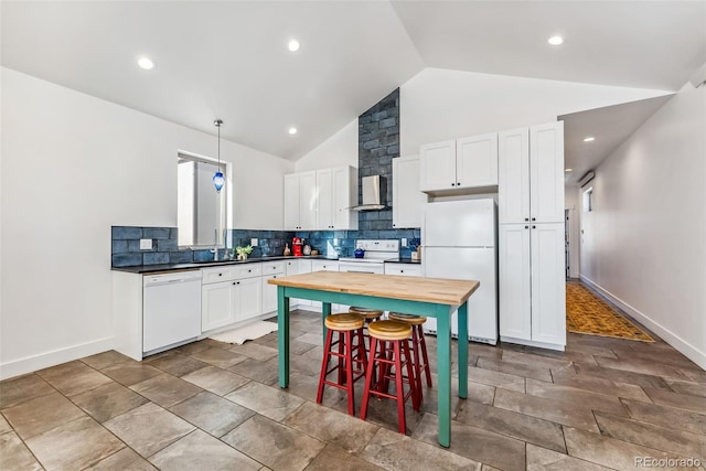 kitchen featuring pendant lighting, white appliances, vaulted ceiling, wall chimney exhaust hood, and white cabinetry