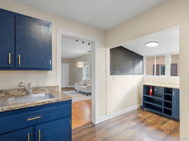 kitchen with blue cabinets, dark hardwood / wood-style floors, and sink