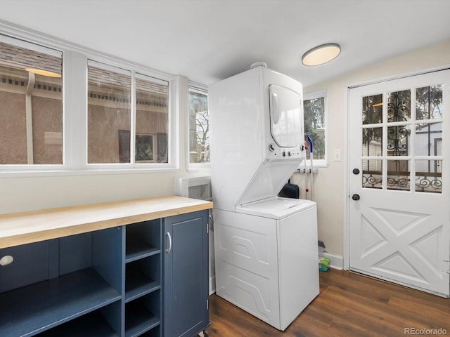 clothes washing area featuring stacked washer and clothes dryer and dark wood-type flooring