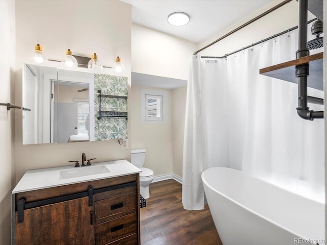 bathroom with hardwood / wood-style floors, vanity, a washtub, and toilet