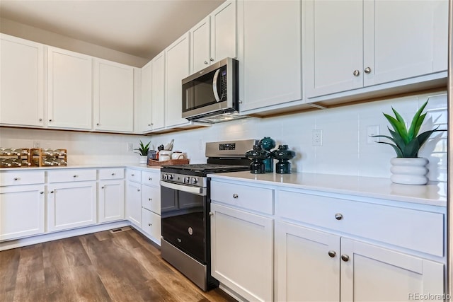 kitchen featuring appliances with stainless steel finishes, dark hardwood / wood-style floors, white cabinets, and decorative backsplash