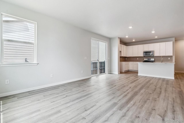 14101 Deertrack Ln, Parker, CO 80134 - unfurnished living room featuring light wood finished floors, baseboards, recessed lighting, and a sink
