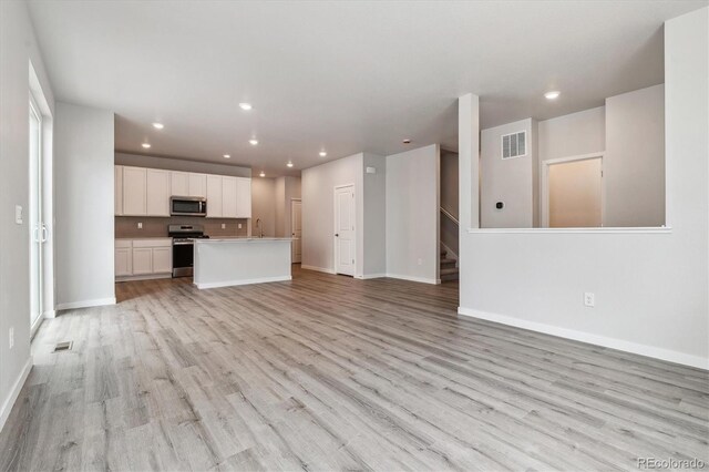 14101 Deertrack Ln, Parker, CO 80134 - unfurnished living room featuring light wood finished floors, baseboards, recessed lighting, stairs, and a sink