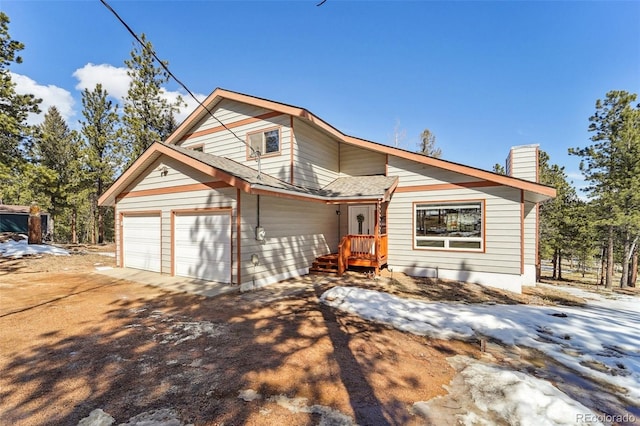 view of front of property with a garage, roof with shingles, driveway, and a chimney