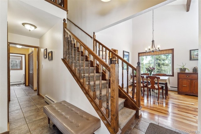 stairway featuring a baseboard radiator, a high ceiling, baseboard heating, and an inviting chandelier