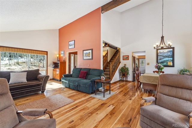 living room with lofted ceiling with beams, light wood-style flooring, stairway, and a wealth of natural light