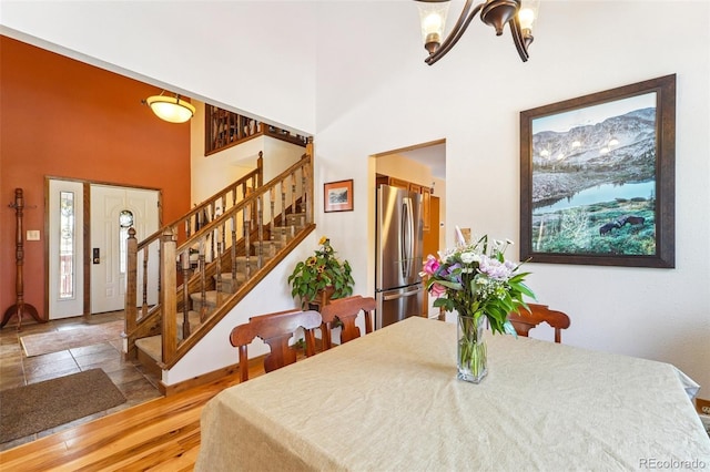 dining room with wood finished floors, plenty of natural light, a high ceiling, and stairs