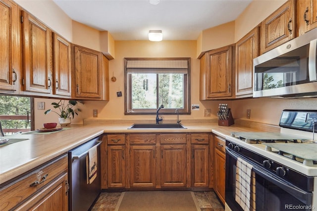 kitchen with stainless steel appliances, a sink, light countertops, and brown cabinets