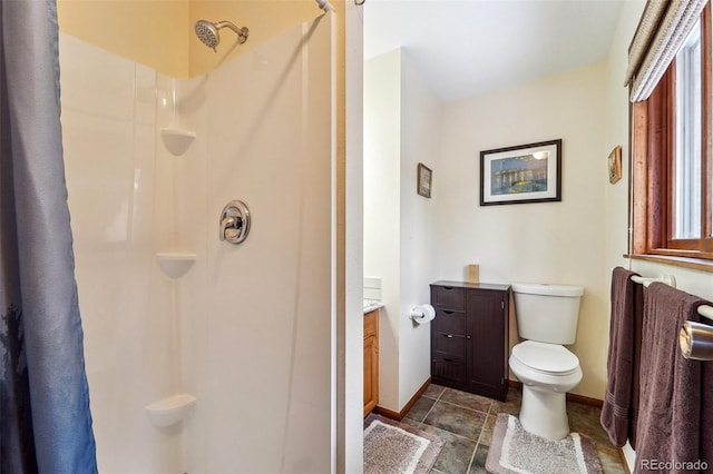 bathroom with toilet, baseboards, a shower, and vanity