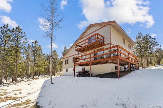 snow covered back of property with a deck