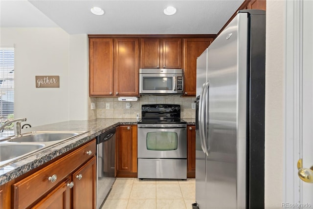 16179 E Geddes Ln Unit 96, Aurora, CO 80016 - kitchen with appliances with stainless steel finishes, light tile patterned floors, tasteful backsplash, dark countertops, and brown cabinets
