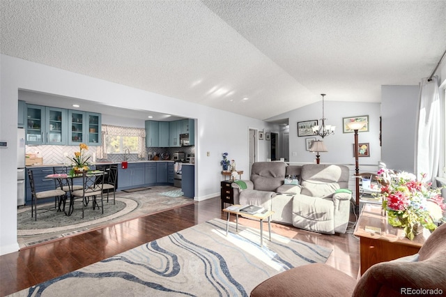 living room featuring baseboards, vaulted ceiling, a notable chandelier, a textured ceiling, and wood-type flooring