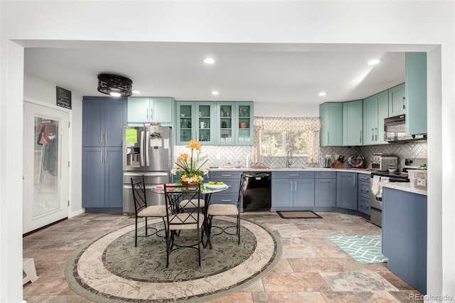 kitchen with black appliances, a sink, tasteful backsplash, stone tile flooring, and light countertops