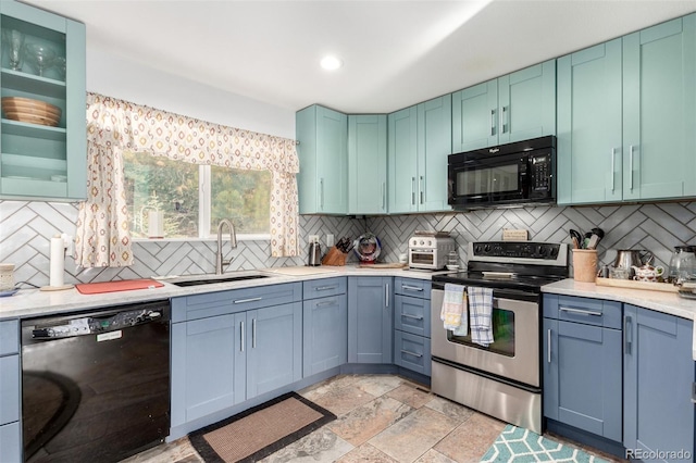 kitchen with decorative backsplash, black appliances, light countertops, and a sink