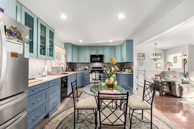 kitchen featuring a sink, black appliances, a wealth of natural light, and light countertops