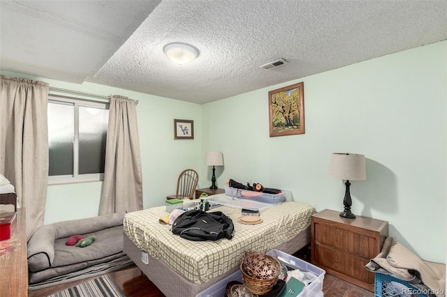 bedroom featuring visible vents, a textured ceiling, and wood finished floors