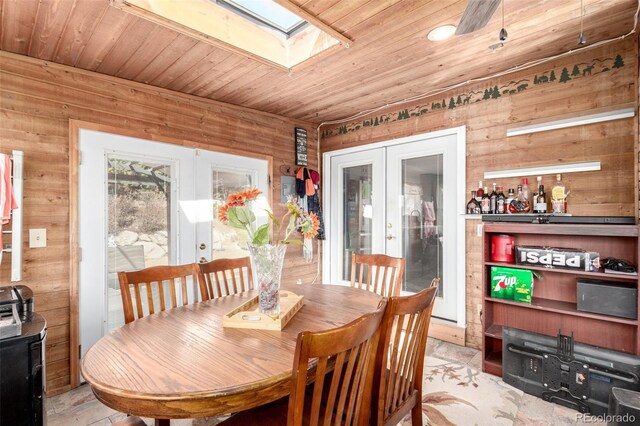 dining room featuring a skylight, french doors, wooden walls, and wooden ceiling