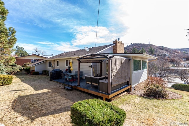 rear view of house with an outdoor living space, a wooden deck, and a chimney