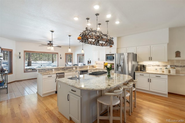 kitchen with stainless steel appliances, a center island with sink, white cabinets, and kitchen peninsula